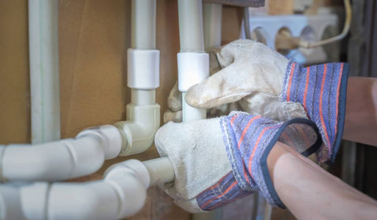 a pair of gloved hands repairing the pipes