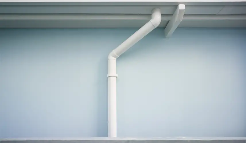 White gutter and rain spouts system on a light blue wall.