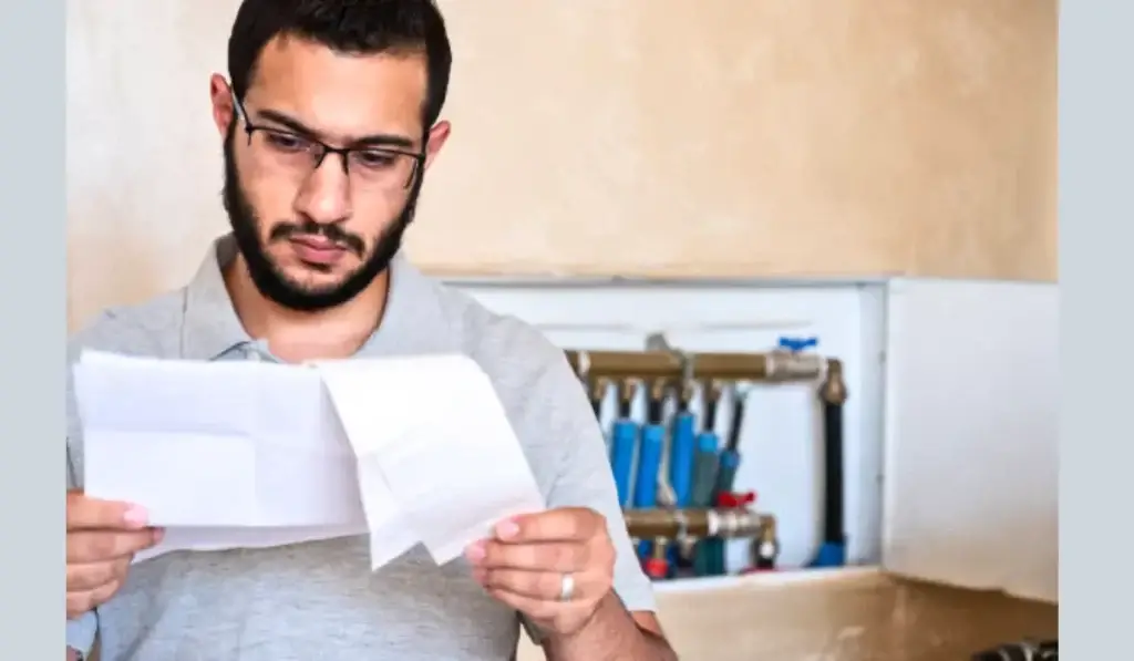 A man examining a plumbing bill, reflecting considerations for how much does a plumber cost in Illinois.