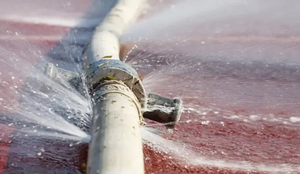 A damaged water pipe bursts, leaking water onto the ground and causing potential water damage.
