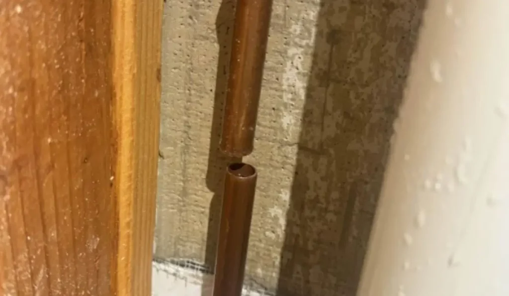 Broken copper pipe inside a Naperville home showing visible split, commonly caused by freezing or high water pressure—used to illustrate burst pipe emergencies.