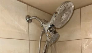 Chrome showerhead with weak spray flow caused by low water pressure inside a Naperville home bathroom.