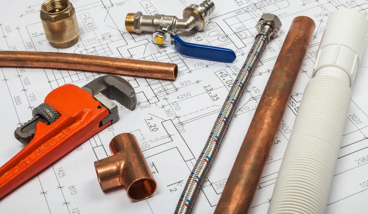 Plumbing tools and pipes on blueprints for a bathroom remodel, showcasing key plumbing upgrades for a Naperville bathroom remodel, including pipe rerouting and fixture installation.
