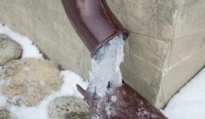 Frozen pipes with heavy ice blockage forming at exterior drain during extreme winter temperatures in Naperville homes.