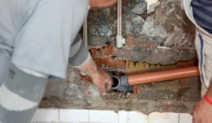 Plumbers repairing interior wall pipes during winter plumbing checklist inspection for Naperville homeowners preparing for cold weather.