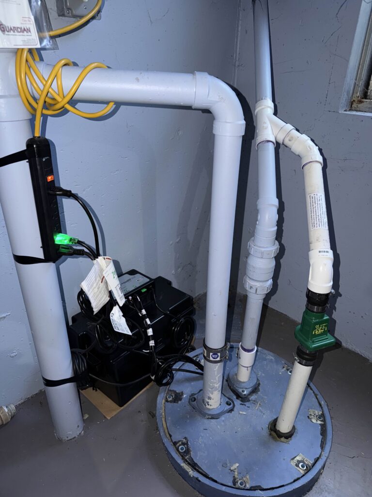 Battery backup sump pump system with PVC piping and check valve installed in a residential basement sump pit.