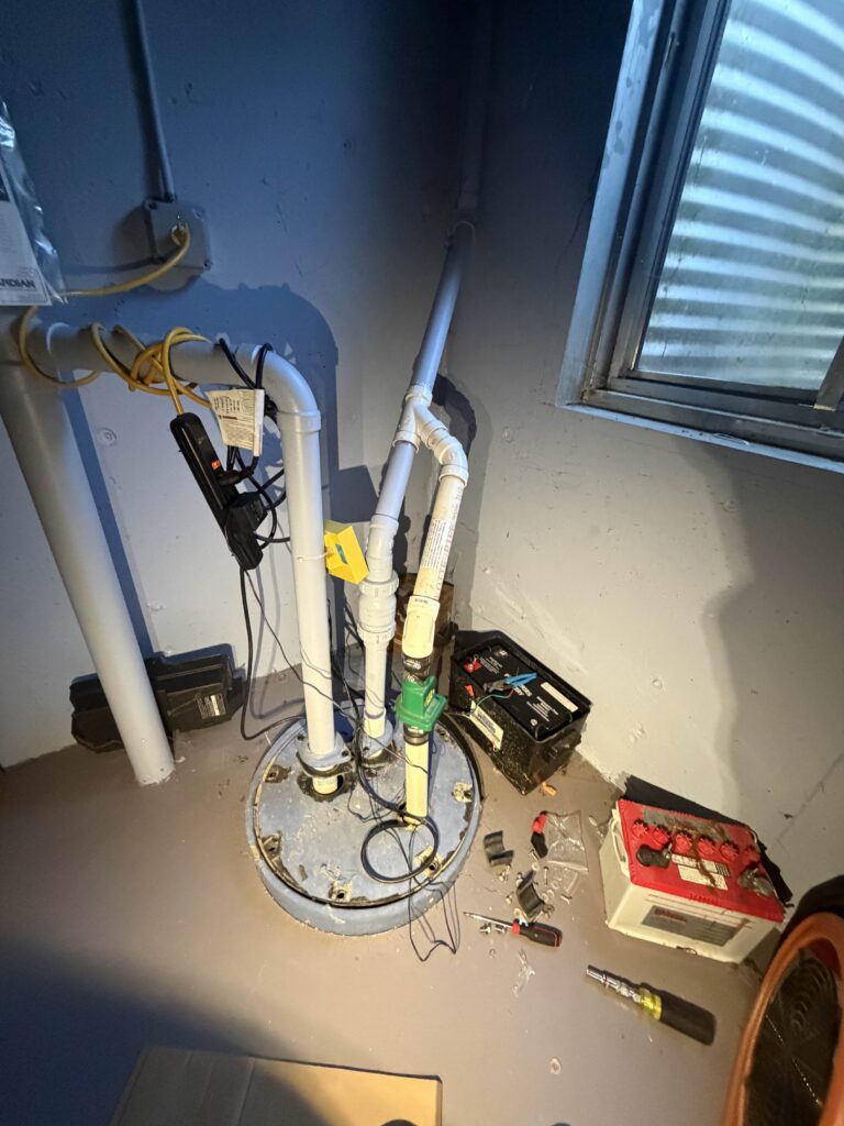 Sump pump replacement with battery backup system installed in a basement sump pit, including PVC discharge piping and check valve.